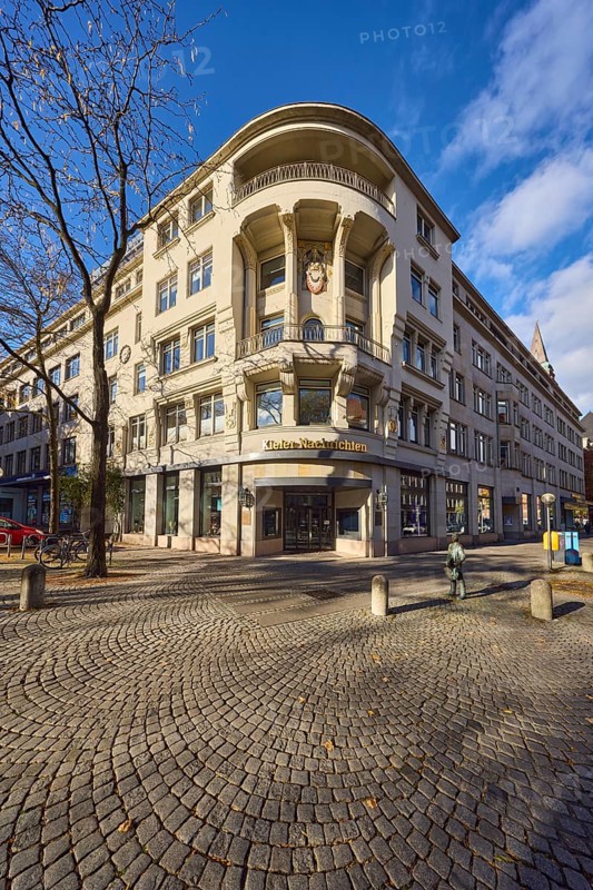 Kieler Nachrichten, Kieler Zeitung Verlags- und Druckerei KG GmbH, historic commercial building, general architecture, paving stone square, barrier bollards, bare winter trees, blue sky, cumulus clouds, Fleethörn and Asmus-Bremer-Platz roads, Kiel, state capital, district-free city, Schleswig-Holstein, Germany