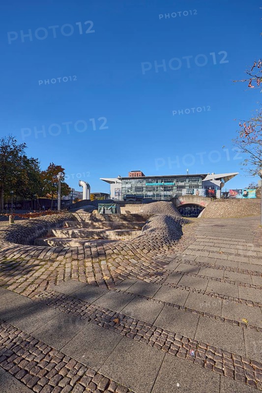 Fountain complex, multi-purpose hall Wunderino Arena or former Baltic Sea Hall, pedestrian zone, lantern, barrier bollard, footpath made of paving stones and cobblestones, trees, blue sky, cloudless, splash, Europaplatz, Kiel, state capital, district-free city, Schleswig-Holstein, Germany