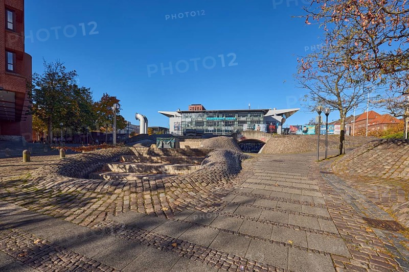 Fountain complex, multi-purpose hall Wunderino Arena or former Baltic Sea Hall, pedestrian zone, lantern, barrier bollard, footpath made of paving stones and cobblestones, trees, blue sky, cloudless, splash, Europaplatz, Kiel, state capital, district-free city, Schleswig-Holstein, Germany