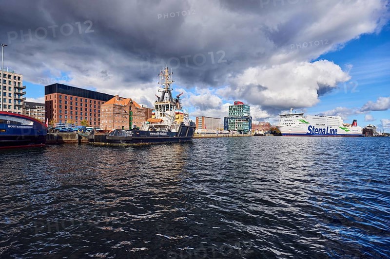 Kiel Fjord, harbour, wharf, ferry Stena Germanica, Stena Line GmbH, harbour tug and sea tug Kiel, tow and ferry company Kiel mbH, general architecture, brick building, commercial building, water surface with small waves, blue sky, cumulus clouds, stratocumulus clouds, white and dark clouds, Kiel, state capital, district-free city, Schleswig-Holstein, Germany