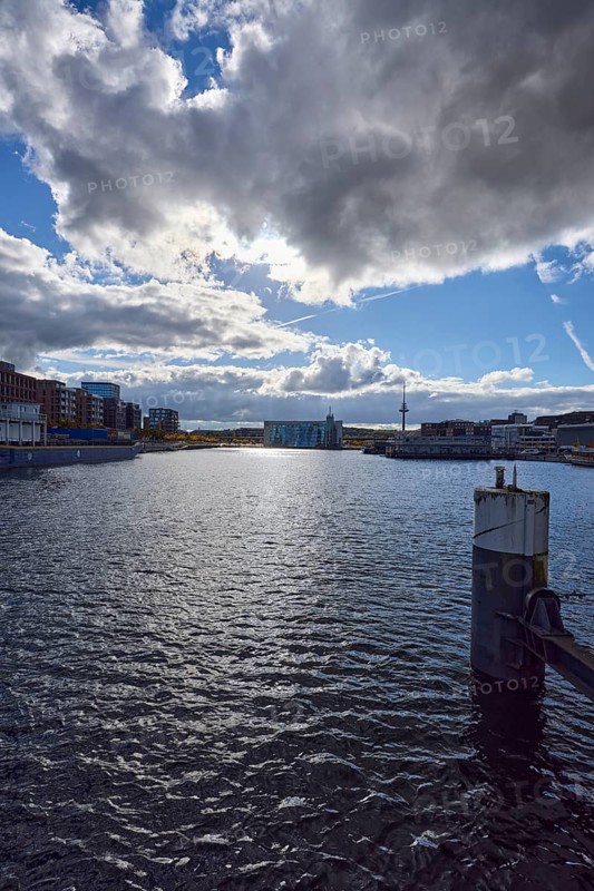 Kiel Fjord, harbor, duckdalben, quay, general architecture, modern buildings, television tower, water surface with small waves, sunny, back light, blue sky, cumulus clouds, stratocumulus clouds, cumulonimbus clouds, white and dark clouds, Willy-Brand-Ufer, Kaistraße, Kiel, state capital, district-free city, Schleswig-Holstein, Germany