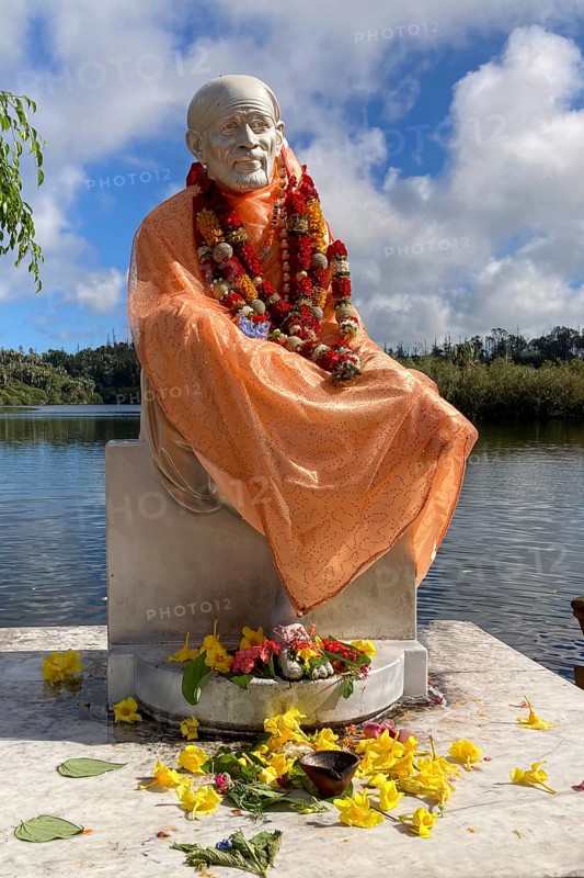 Statue of Indian spiritual master Hindu monk Shirdi Sai Baba, stands on the edge of in sacred Hindu lake Ganga Talao at religious site largest Hindu shrine for religion Hinduism outside India for devout Hindu Hindus, in the background Sacred Lake Ganga Talao crater lake in crater of extinct volcano, Grand Bassin, Le Pétrin, Mauritius