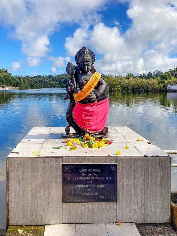 Statue sculpture of war deity Muruga, son of Shiva and Parvati, also revered as the god of the Tamil Tamil Kadavul, symbolizes courage wisdom and victory over evil, stands in holy Hindu lake Ganga Talao at religious site largest Hindu shrine for religion Hinduism outside India for believers Hindu Hindus, in the background Sacred Lake Ganga Talao crater lake in crater of extinct volcano, Grand Bassin, Le Pétrin, Mauritius