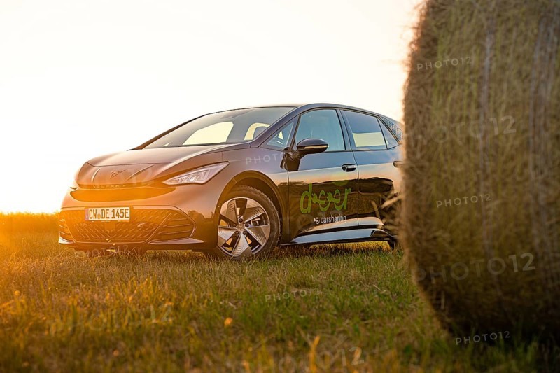 Car next to a hay bale in a rural landscape at sunset, electric car Cupra, e-car sharing, Calw, Germany