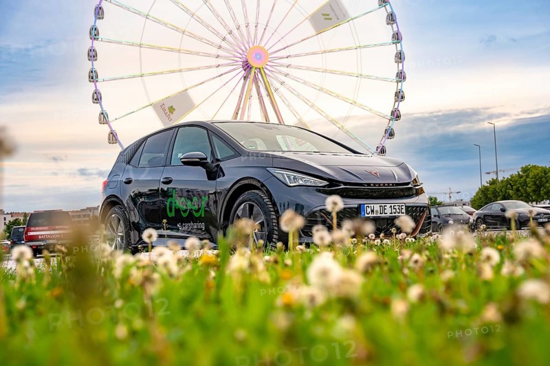 Car on a green field with a Ferris wheel in the background, electric car Cupra, e-car sharing, Calw, Germany