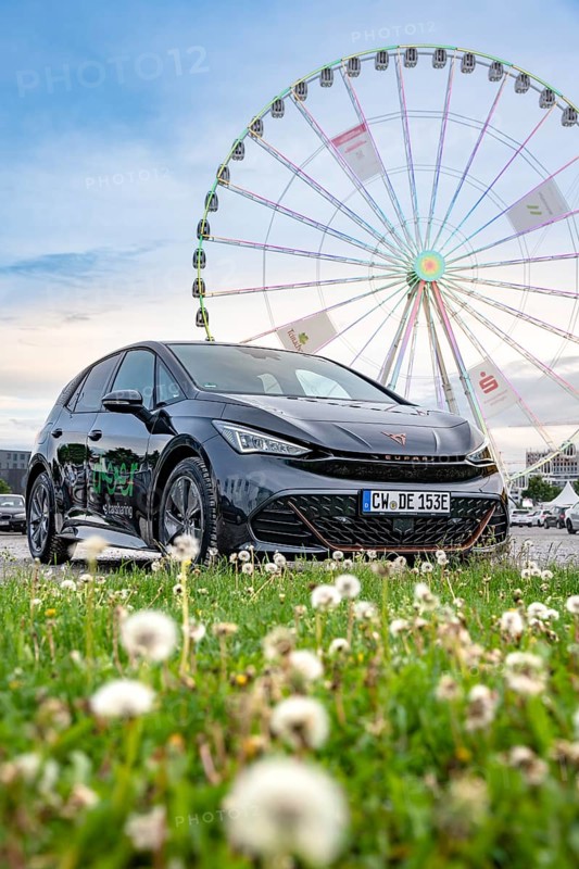 Car in a meadow with Ferris wheel in the background and flowers in the foreground, electric car Cupra, e-car sharing, Calw, Germany
