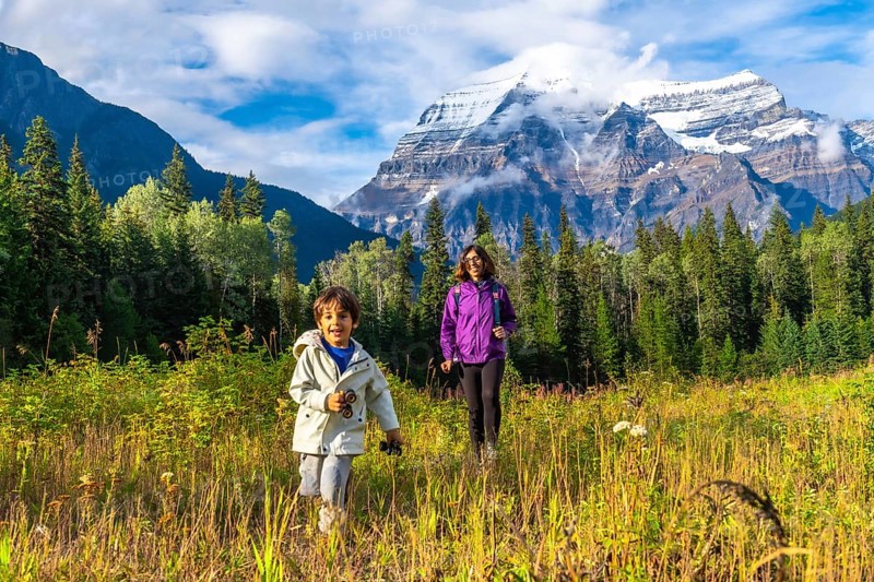 Mother and son are hiking in a meadow near mount robson, enjoying the stunning view of the canadian rockies in british columbia, canada, on a beautiful sunny day