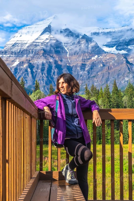 Female hiker relaxing and enjoying the majestic view of mount robson, the highest peak in the canadian rockies, british columbia, canada, during a sunny day