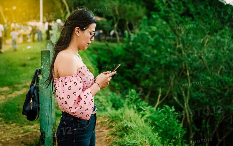 Latin woman checking her cell phone, pretty girl in glasses checking her cell phone