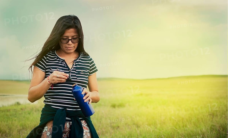 Girl in the field drinking water. Concept of woman in the field drinking water