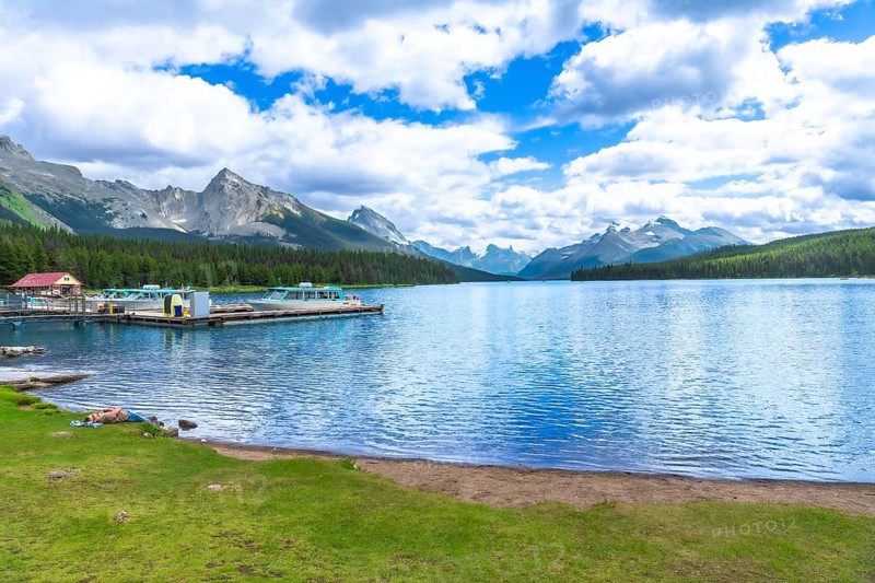 Tranquil maligne lake in jasper national park reflecting the majestic canadian rockies, with boats docked at spirit island, offers breathtaking views of pristine nature