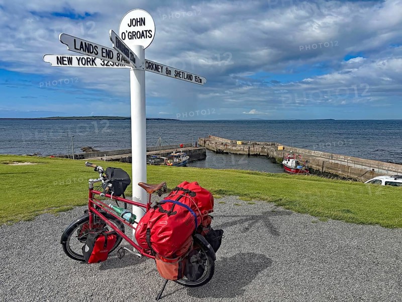 Packed bike in front of lake sign and harbor view in John O'Groats, bicycle trips, bicycle adventures, Scotland, Great Britain