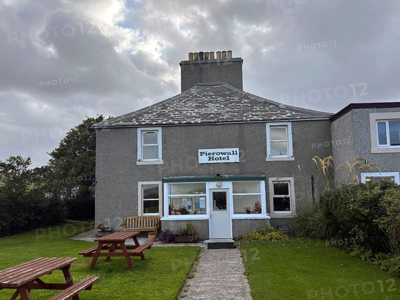 Classic hotel view under cloudy sky with green surroundings and picnic tables, only hotel on Westray Island, Orkney Islands, Scotland, Great Britain