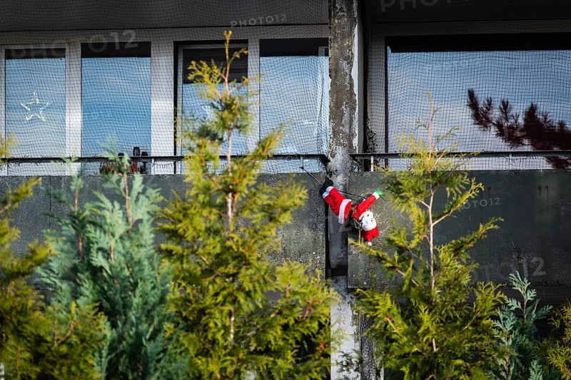 A Santa Claus figure hangs on a concrete behind fir trees, Wuppertal, Germany
