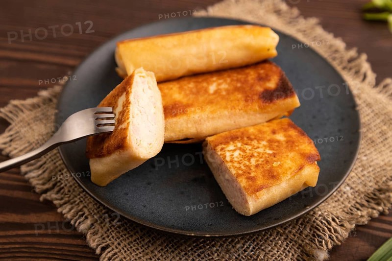 Fried crispy pancakes with meat and cheese on brown wooden background and linen textile. side view, close up, selective focus
