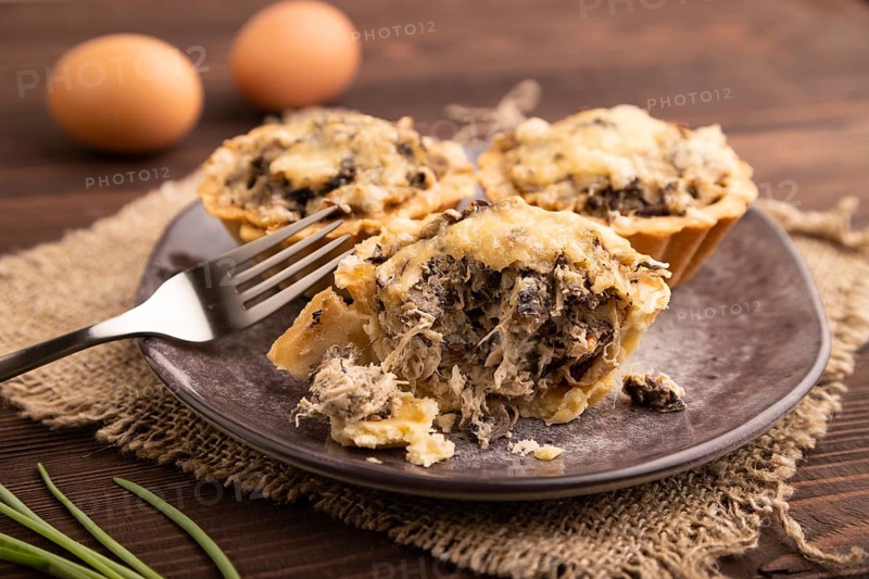 Tartlets with meat and cheese on brown wooden background and linen textile. side view, close up, selective focus