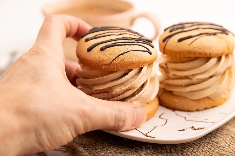 Caramel Cream Cakes with hand on white wooden background and linen textile, cup of coffee, side view, close up, selective focus
