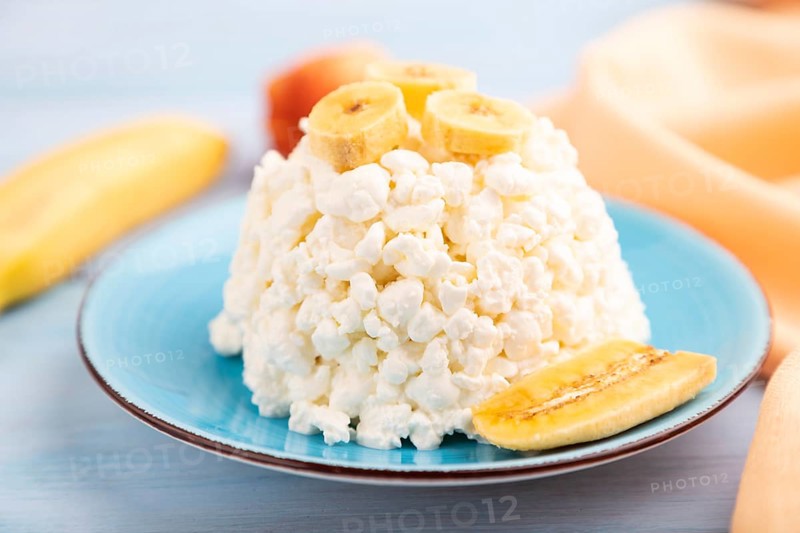 White ?ottage cheese, Curd, with Banana on blue wooden background and orange textile, side view, close up, selective focus