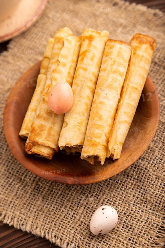 Waffles with caramel on brown wooden background and linen textile, cup of coffee, side view, selective focus