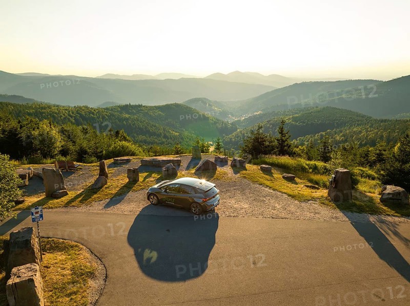 Car parked at a viewing point with a wide view over a mountainous forest area at sunset, deer e-car sharing, Cupra electric car, Bad Wildbad, Germany