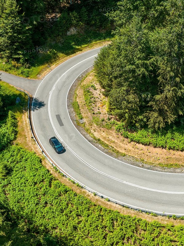 Car on a winding road in the forest, taken from a bird's eye view, Deer E-car sharing, Cupra electric car, Germany