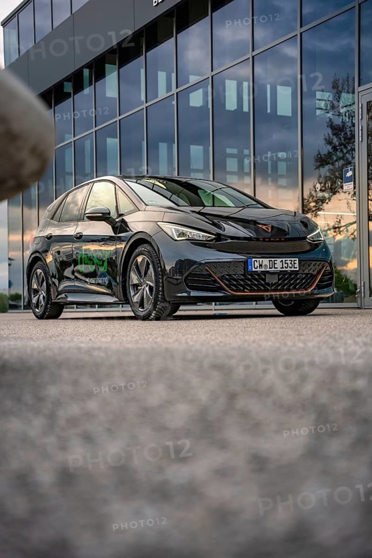 Black car in front of a modern building with glass façade, photographed on concrete floor, Deer E-Car Sharing, Cupra electric car, Böblingen, Germany