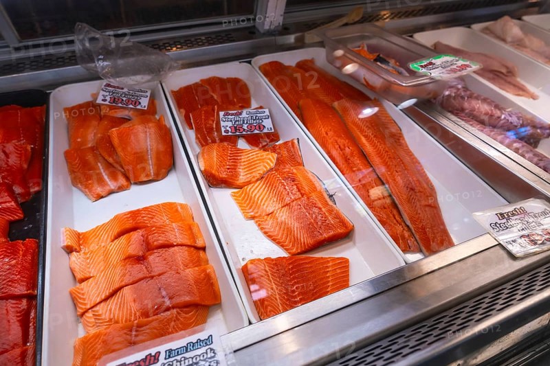 Fresh salmon fillets, cut into steaks and portions, are displayed on ice in a fish market in vancouver, canada, ready for sale to customers seeking high quality seafood
