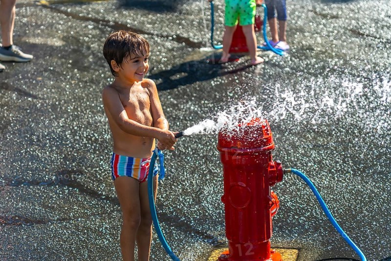 Happy child spraying water from a fire hydrant during a hot summer day in vancouver, british columbia, enjoying a playful moment of refreshment and fun