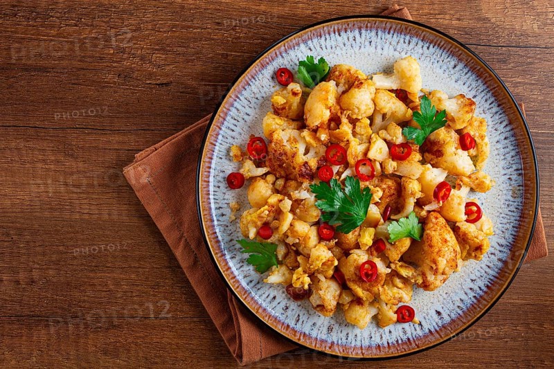 Spicy fried cauliflower served on a wooden countertop