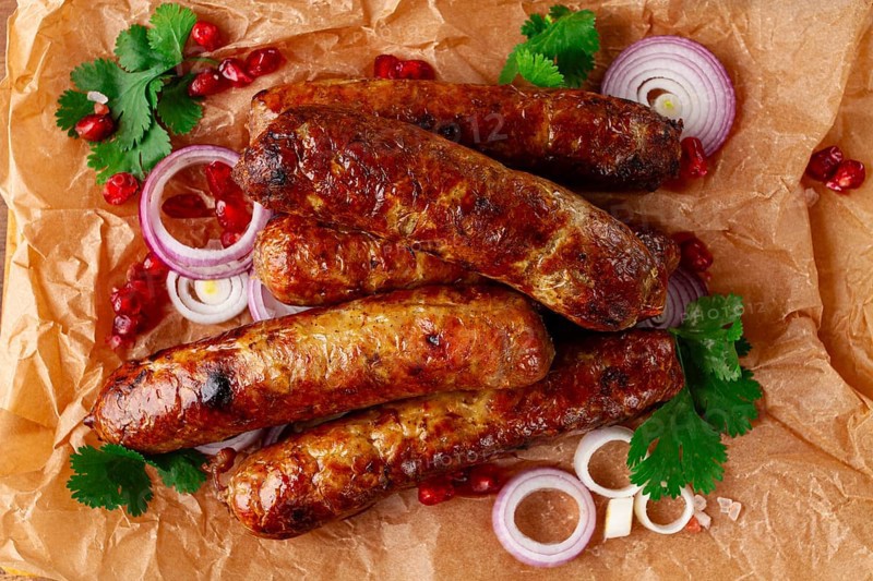 Fried kupaty on parchment, with red onion and pomegranate, kupaty, Georgian cuisine