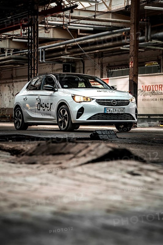 A small car against an industrial backdrop with structured elements and rugged charm, Deer E-Car Sharing, Motorworld Rüsselsheim, Germany