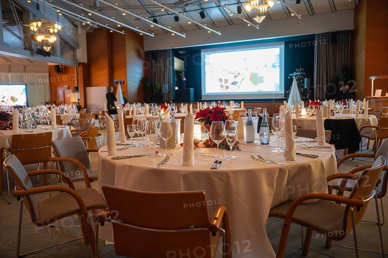 A tastefully furnished room with set tables and a large screen, Christmas party Dekra Congresshotel Wart, Calw district, Germany