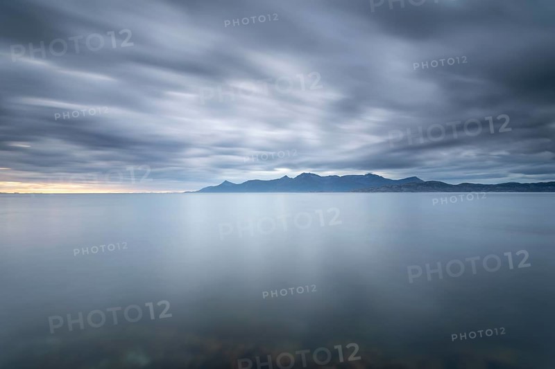 The Vestfjord in Nordland, Norway, near Bodø, impresses with a dramatic atmosphere. Dark clouds sweep across the water and create a mystical atmosphere. The rugged cliffs and majestic mountains are reflected in the tranquil fjord and provide an impressive backdrop