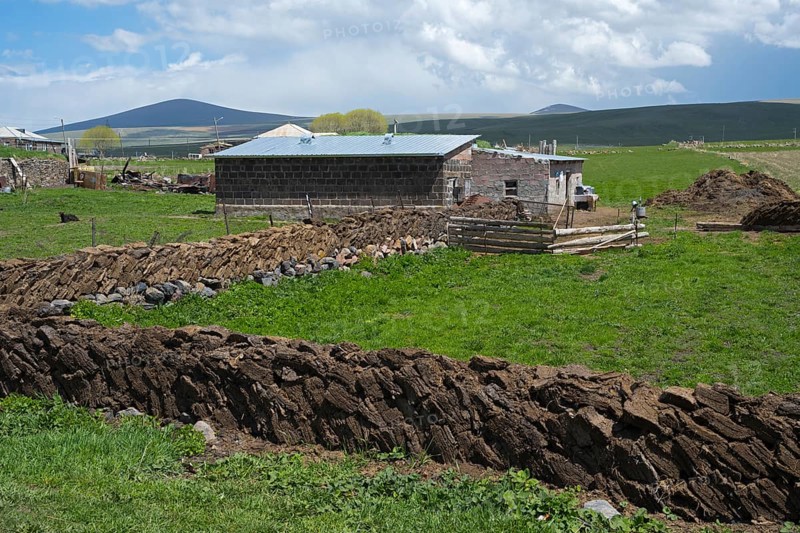 Farm with natural stone structures and green meadow in rural surroundings, cow dung walls, Samtskhe—Javakheti region, Samtske Javacheti, Lesser Caucasus, Georgia