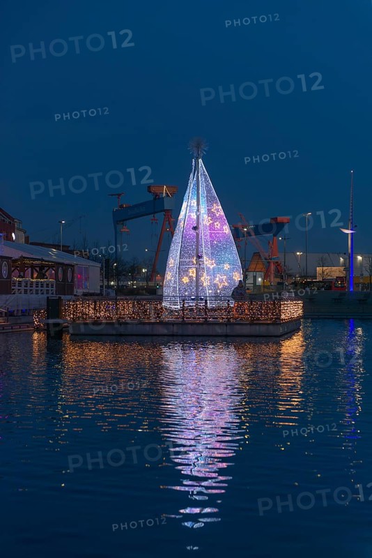 Christmas decoration in Kiel at the boat harbor, festive lighting, glow of lights, evening, darkness, island of lights, shipyard on the fjord, Christmas tree with stars, water reflection, Schleswig-Holstein, Germany