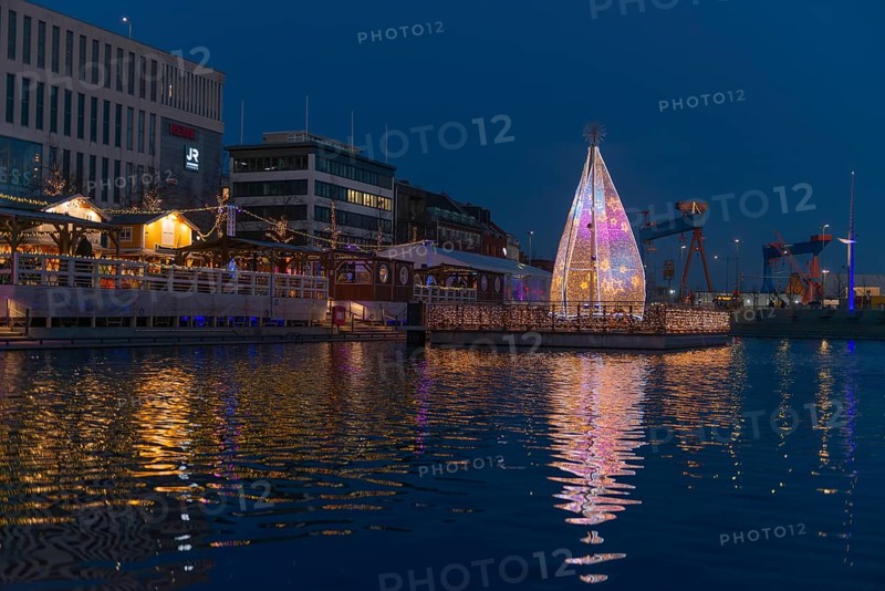 Christmas decoration in Kiel at the boat harbor, festive lighting, glow of lights, evening, darkness, shops, island of lights, shipyard on the fjord, Christmas tree with stars, water reflection, Schleswig-Holstein, Germany
