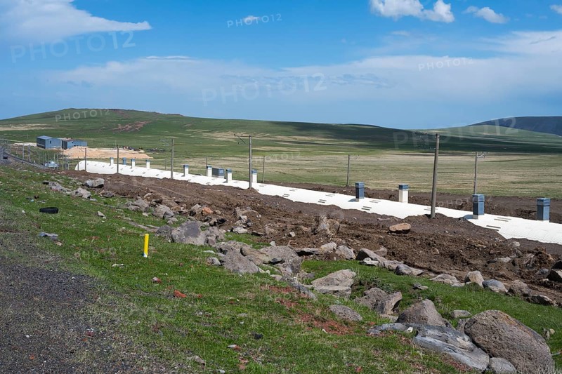Wide landscape with green field and blue sky, in the foreground a road and a covered railway track, partly covered railway line on Lake Parawani, in the highlands of Samtskhe—Javakheti, Samtskhe-Javakheti, Lesser Caucasus, Georgia