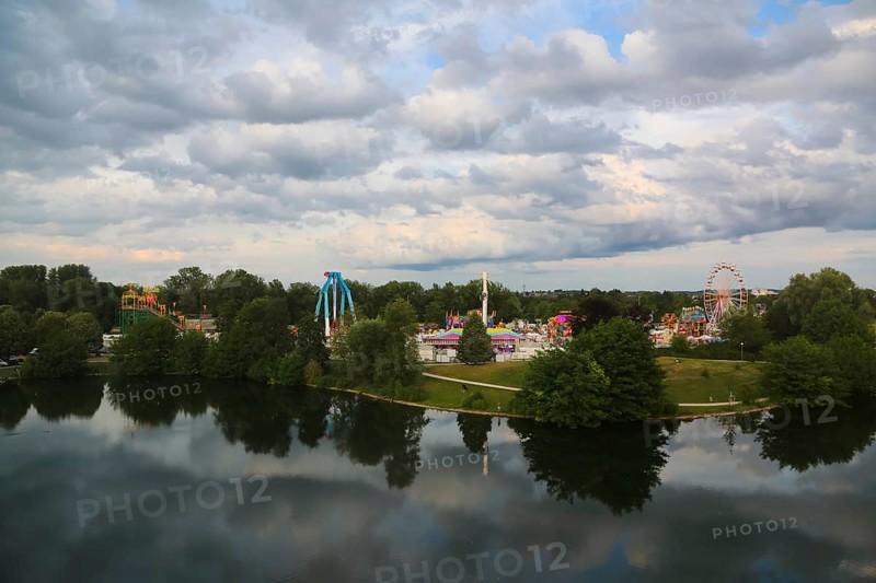 Fairground in Ulm Friedrichsau, folk festival, hustle and bustle, Ferris wheel, amusement park, amusement attraction, ride, gray clouds, reflection in the natural lake, Ausee, Ferris wheel, Ulm, Baden-Württemberg, Germany