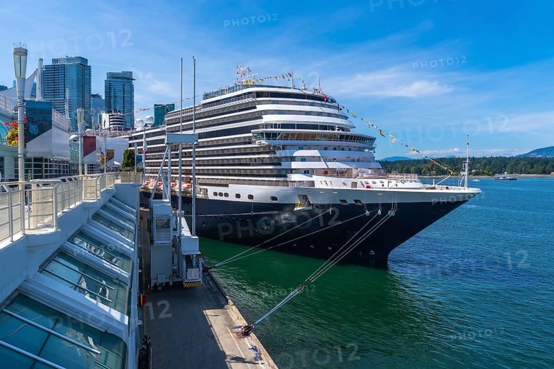 Large cruise ship docking at canada place cruise terminal in vancouver, british columbia, with city skyline and harbor in background on a sunny day