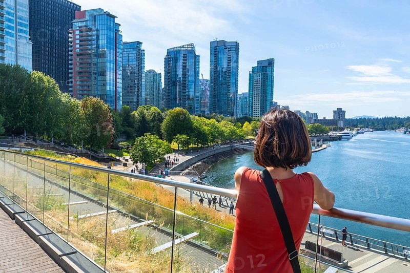 Tourist is enjoying the scenic view of vancouver skyline from david lam park in yaletown, vancouver, british columbia, canada during a sunny summer day