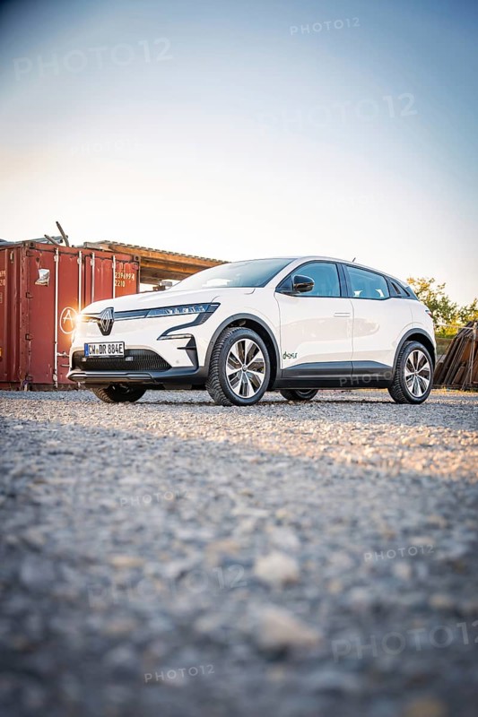 A white electric car stands in front of a container on a gravel field at dusk, Deer E-Carsharing, Renault Megane, Calw, Germany