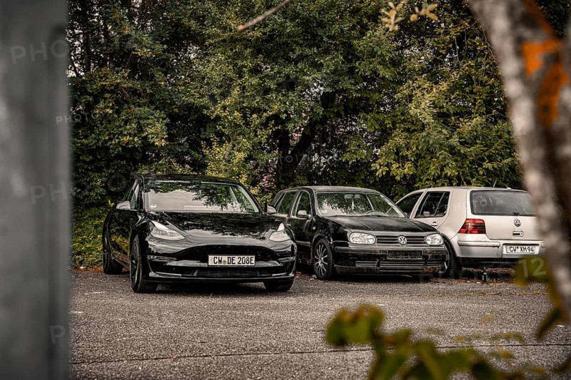 Parking lot with black cars surrounded by thick vegetation, deer e-car sharing, Tesla Model 3, Calw, Germany