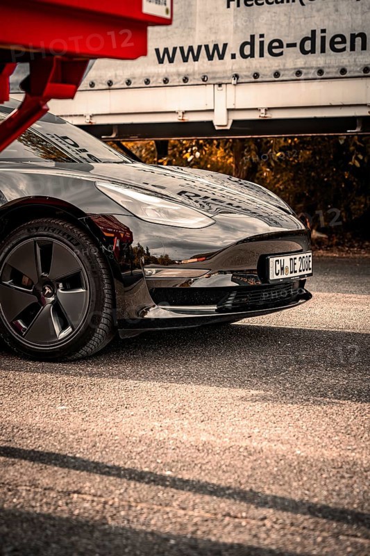 Close-up of a black car with shiny paint and visible reflection on the asphalt, Deer E-Carsharing, Tesla Model 3, Calw, Germany