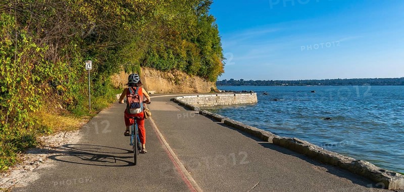 Tourist cycling through stanley park, soaking in stunning ocean views and vibrant cityscapes of vancouver, british columbia, during a sunny summer day filled with adventure