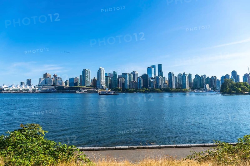 Panoramic view of vancouver's modern skyline rising above the calm pacific ocean on a sunny day, creating a vibrant urban landscape