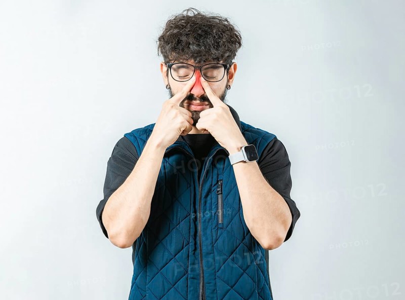Man with rhinitis touching nose. Person with sinus pain touching nose isolated