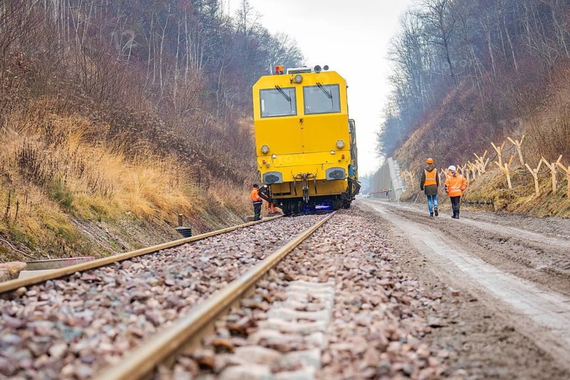 Yellow vehicle on rails with construction workers on a gravel path in the forest, stuffing machine on Hermann, Hesse, railway, Althengstett, Calw district, Germany