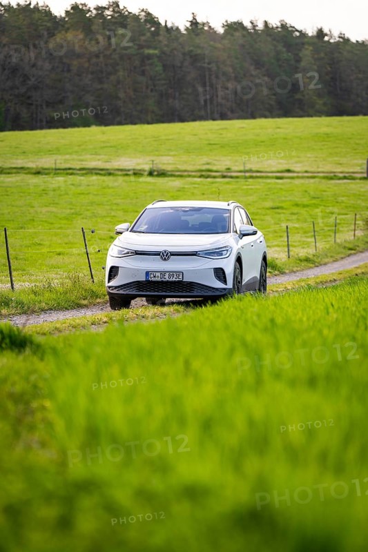 SUV on a path between vast green fields, deer e-car sharing, VW ID4, Calw, Germany