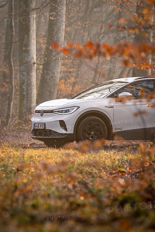 A white car drives on a forest path surrounded by autumn trees, Deer E-Carsharing, VW ID4, Calw, Germany