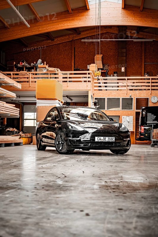 Black car parked in a wood-panelled workshop with modern architectural design, Deer e-car sharing, Tesla Model 3, Calw, Germany